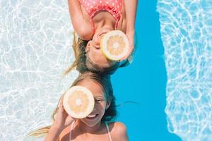 adoráveis irmãzinhas brincam na piscina ao ar livre foto