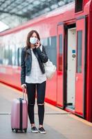 jovem turista com bagagem na plataforma esperando o trem foto