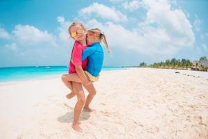 duas meninas felizes se divertem muito na praia tropical brincando juntas foto