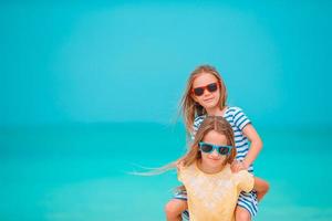 duas meninas felizes se divertem muito na praia tropical brincando juntas foto