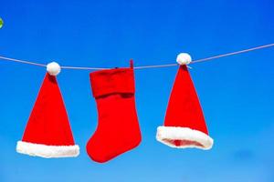 chapéus de papai noel vermelhos e meia de natal pendurado na praia tropical foto