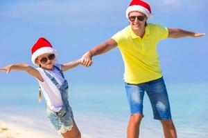 menina e pai feliz em chapéus de Papai Noel aproveitam as férias de natal foto