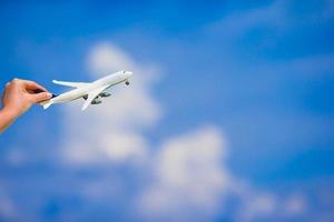 pequeno modelo de avião branco em fundo de mão feminina do mar turquesa foto