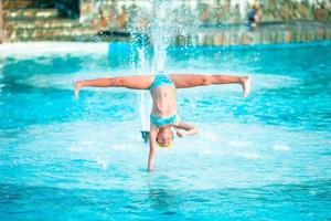 menina feliz aproveite as férias na piscina. garoto esportivo fazendo estrela na beira da piscina foto