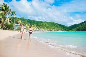 crianças se divertindo na praia tropical durante as férias de verão brincando juntos. meninas correndo em águas rasas foto