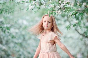 menina adorável no jardim de cerejeiras florescendo na primavera foto