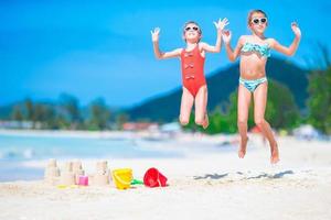 duas crianças fazendo castelo de areia e se divertindo na praia tropical foto