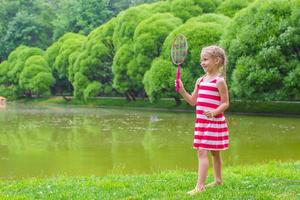 menina bonitinha jogando badminton no piquenique foto