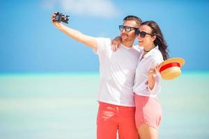 casal feliz tirando uma foto na praia branca nas férias de lua de mel