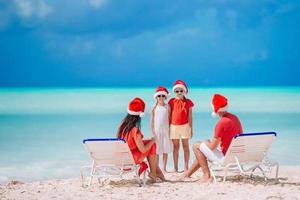 família feliz com dois filhos com chapéu de Papai Noel nas férias de verão foto