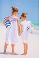 adoráveis meninas com toalhas de praia na praia tropical branca foto