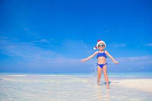 menina feliz com chapéu de papai noel durante as férias de praia nas maldivas foto