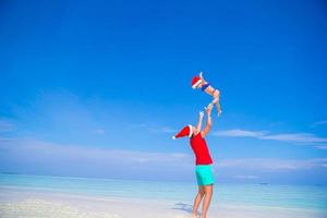 menina e pai feliz no chapéu de papai noel durante as férias de natal na praia foto