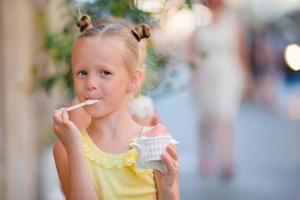 menina comendo sorvete ao ar livre no verão. garoto bonito desfrutando de gelato italiano real perto de gelateria em roma foto