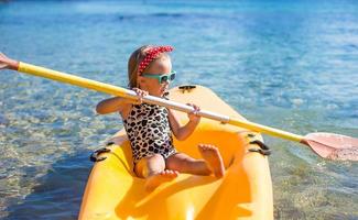 menina bonitinha gosta de nadar no caiaque amarelo em água turquesa clara foto