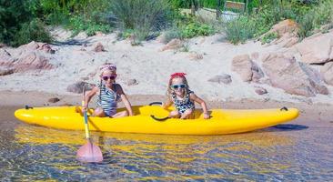 meninas adoráveis desfrutando de caiaque na água azul-turquesa foto