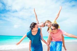 família feliz com crianças caminha na praia foto