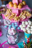 marshmallow, merengues coloridos doces, pipoca, bolos de nata e bolo branco aparece na mesa do deserto foto