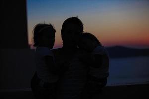 silhuetas de pai e filha no pôr do sol na velha cidade grega foto