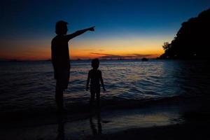 silhuetas de pai e filha no pôr do sol na praia em boracay, filipinas foto