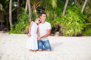 pai com filha relaxando na praia branca foto