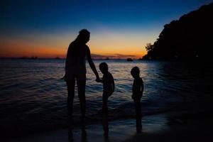 família de três silhuetas por do sol na praia de boracay foto