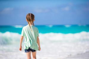 vista traseira da adorável garotinha na praia foto