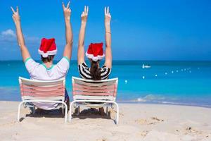 jovem casal romântico em chapéus de Papai Noel durante as férias na praia foto