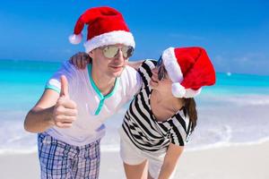 jovem casal romântico em chapéus de Papai Noel durante as férias na praia foto