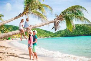 crianças se divertindo sentado na palmeira. família feliz relaxando na praia tropical de carlisle bay com areia branca e água turquesa do oceano na ilha de antígua, no caribe foto