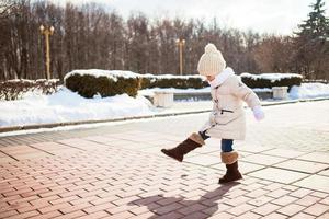 menina bonita caminha no inverno em um dia ensolarado ao ar livre foto