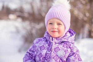 retrato de uma menina bonita e feliz na neve ensolarada dia de inverno foto