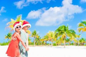 crianças felizes se divertem com chapéu de Papai Noel durante as férias na praia de natal. ano novo na praia foto