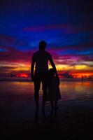 silhuetas de pai e filha no pôr do sol na praia de boracay foto