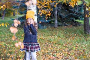 menina brincando de esconde-esconde na floresta de outono foto