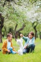 garotinhas sorridentes brincando e abraçando o cachorrinho no parque foto