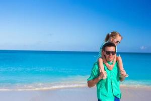 adorável menina se divertir com o pai durante a praia tropical foto