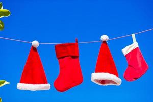 chapéus de papai noel vermelhos e meia de natal pendurado na praia tropical foto