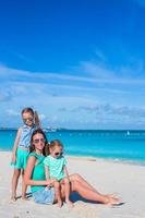 meninas e mãe feliz durante as férias na praia tropical foto