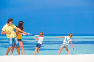 família feliz se divertindo na praia branca foto