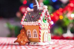 casa de gengibre decorada por doces doces em um fundo de árvore de natal brilhante com guirlanda foto