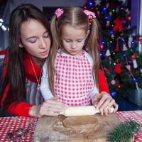 família feliz em chapéus de papai noel assando biscoitos de gengibre de natal juntos foto