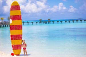 adorável menina com grande prancha de surf durante as férias tropicais foto
