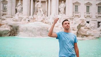 jovem perto da fonte fontana di trevi com moedas nas mãos foto