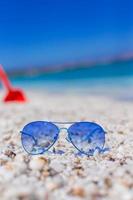 close-up de óculos de sol azuis coloridos na praia tropical foto