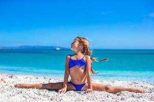 menina fazendo divisão de perna na praia de areia branca tropical