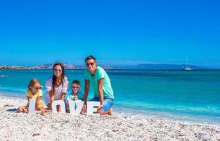 jovem linda família de quatro pessoas com a palavra amor na praia foto