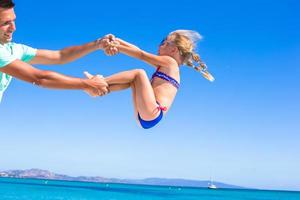 menina feliz se diverte com o pai durante as férias na praia foto