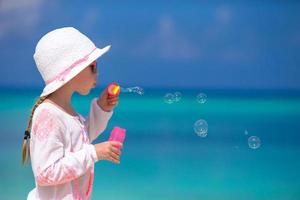 adorável menina fazendo bolhas de sabão durante as férias de verão foto