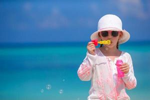 adorável menina fazendo bolhas de sabão durante as férias de verão foto